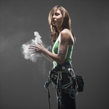 Woman with climbing gear putting chalk on hands