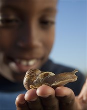Young boy holding snail