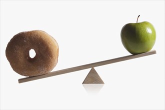 Donut and apple balanced on teeter totter
