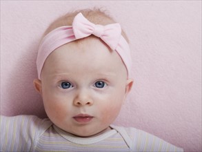 Portrait of baby girl with pink ribbon
