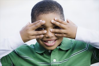 Boy with hands in front of eyes