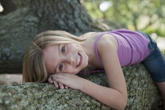 Girl lying down on tree