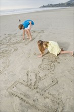 Children writing on beach
