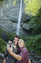 Couple taking picture in front of waterfall