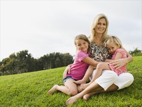 Mother and daughters sitting on grass