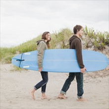 Couple carrying surfboard