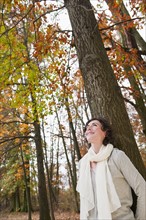 Woman leaning on tree.