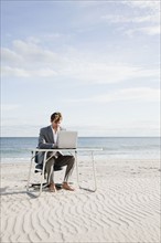 Businessman working at desk on the beach