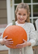 Girl holding pumpkin.