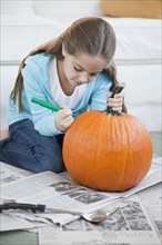 Young girl drawing on pumpkin. Photographer: Jamie Grill