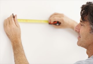 Carpenter measuring wall. Photographer: momentimages