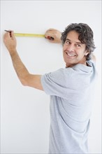 Carpenter marking straight line on wall. Photographer: momentimages