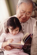 Grandfather reading to granddaughter. Photographer: Rob Lewine
