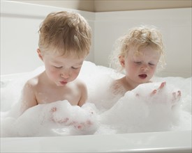 Children playing with bubbles in the bath tub. Photographer: Mike Kemp