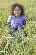 Young girl sitting in tall grass. Photographer: Pauline St.Denis