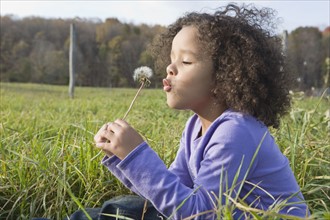 Young girl blowing dandelion. Photographer: Pauline St.Denis