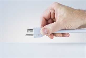 Hand holding plug.