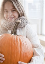 Young girl holding pumpkin. Photographer: Jamie Grill