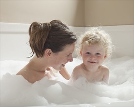 Mother and child having bubble bath. Photographer: Mike Kemp