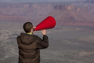 Man using megaphone at top of canyon. Photographer: Dan Bannister
