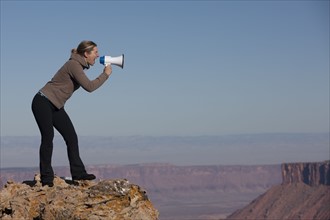 Woman yelling into megaphone at top of canyon. Photographer: Dan Bannister