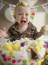 Baby covered in birthday cake. Photographer: Mike Kemp
