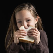 Young girl eating a sandwich. Photographer: Mike Kemp