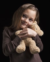 Young girl hugging teddy bear. Photographer: Mike Kemp
