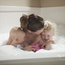Mother and children having bubble bath. Photographer: Mike Kemp