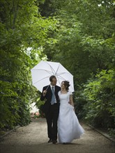Bride and groom walking in the rain. Photographer: Mike Kemp
