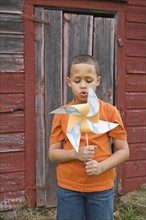 Boy blowing toy windmill. Photographer: Pauline St.Denis