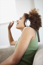 Woman listening to music on headphones. Photographer: momentimages