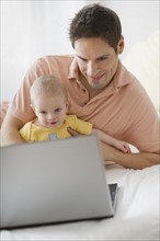 Father and baby looking at laptop.