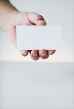Hand holding white card.