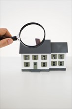 Looking at toy house with magnifying glass.