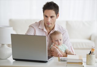 Man holding baby while working.