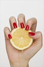 Hand holding slice of lemon.