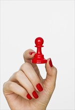 Hand holding red pawn chess piece.