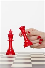 Hand holding red chess piece.
