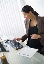 Pregnant businesswoman working on computer.