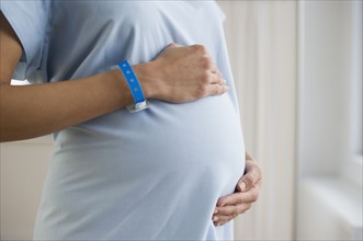 Pregnant woman wearing hospital gown.