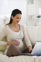 Pregnant woman looking at laptop.