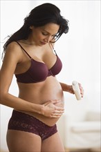 Pregnant woman putting moisturizing cream on her belly.