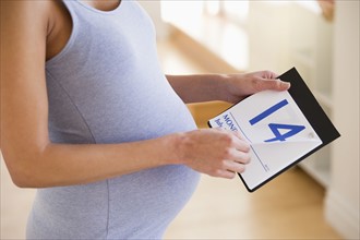 Pregnant woman looking a calendar.