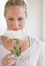 Woman smelling a white flower.