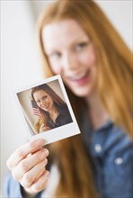 Woman holding photograph of herself.