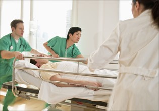 Healthcare workers pushing gurney in emergency room.