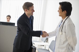 Salesman and doctor shaking hands.