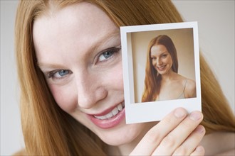Woman holding a photograph of herself.