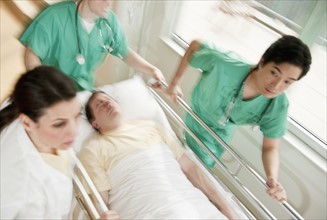Healthcare workers pushing gurney in emergency room.